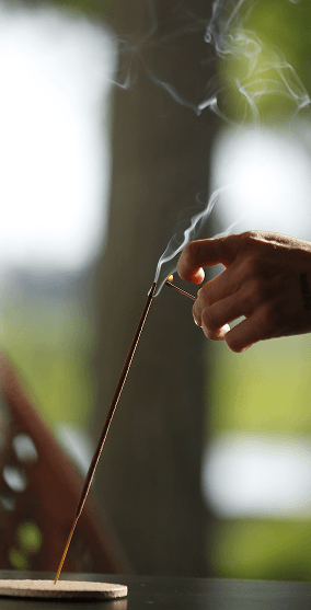 A hand holding burning incense
