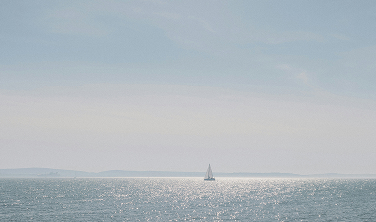 A sailboat on a calm sea in the morning haze