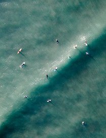 Surfers on turquoise water, seen from above